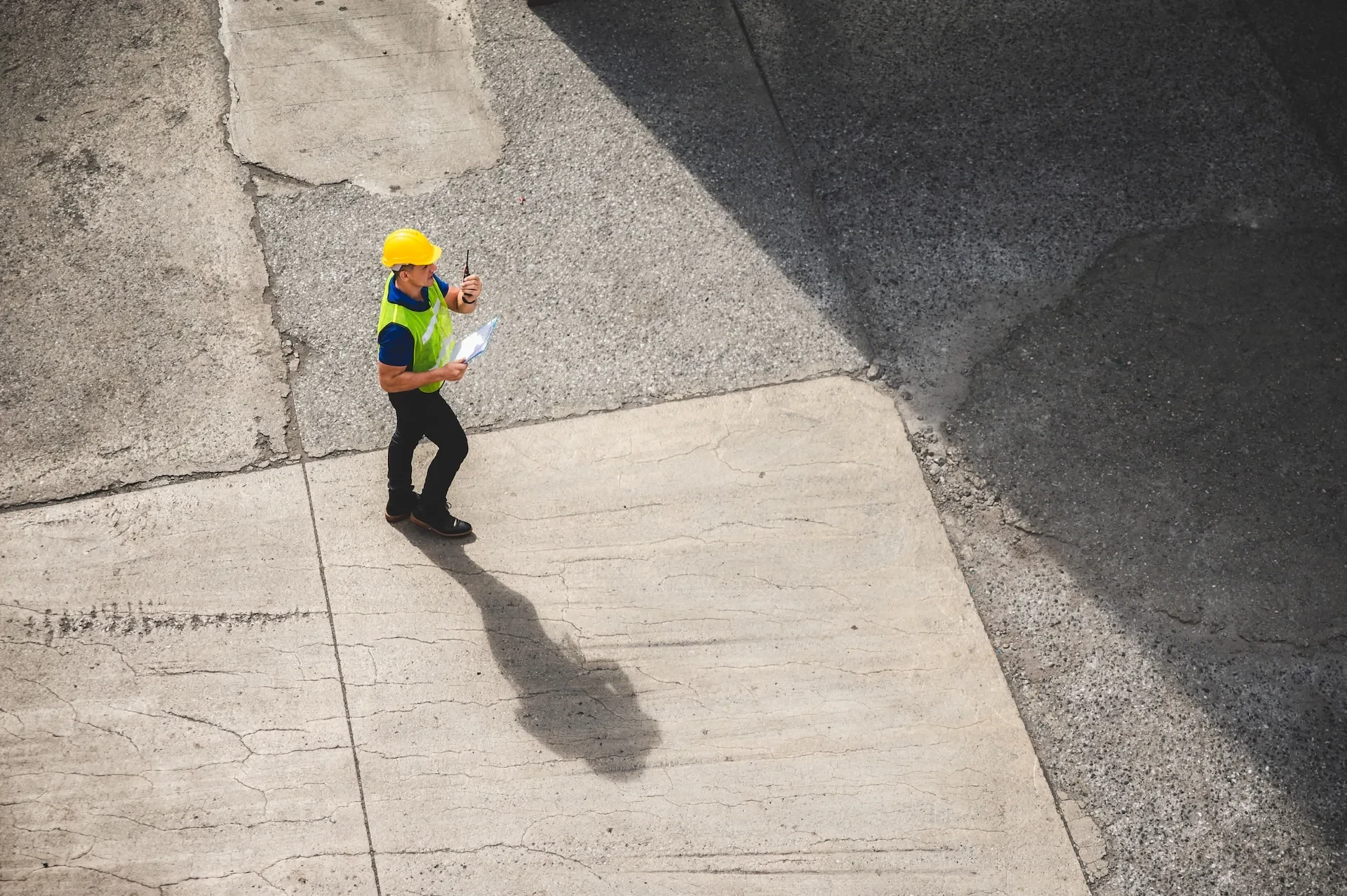 A site manager crossing an industrial yard at the start of a shift.